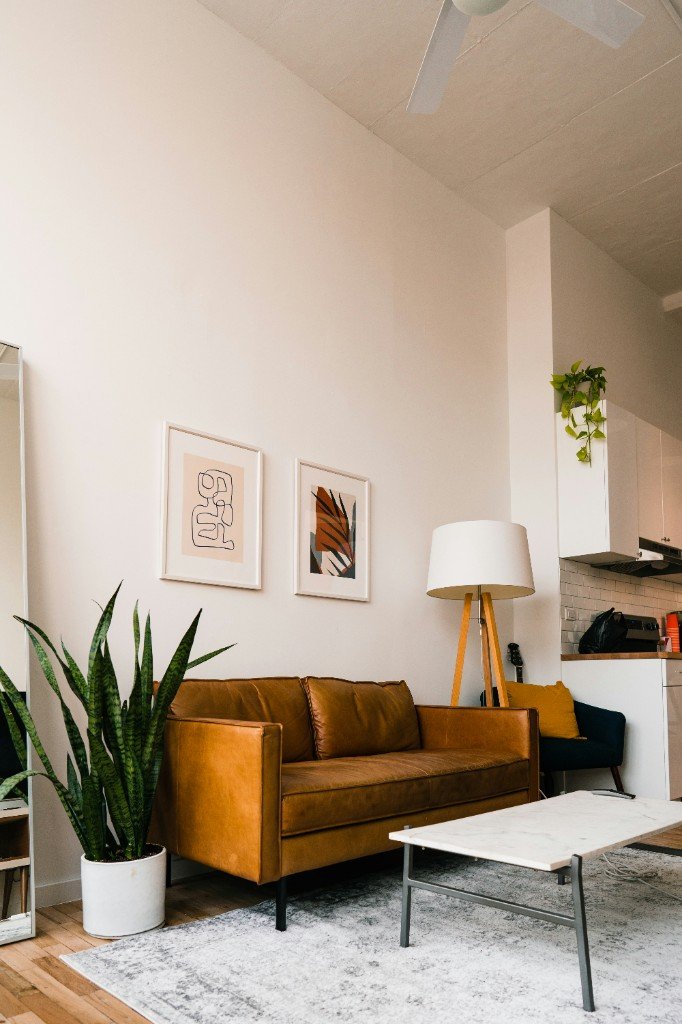Bright living room with cognac leather sofa, marble coffee table, and indoor plants