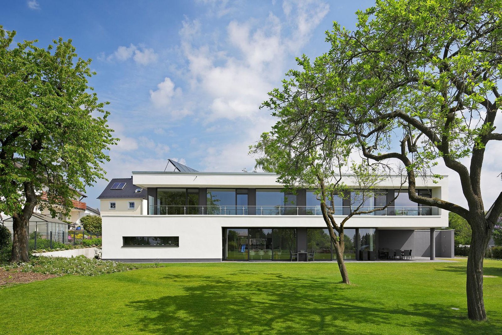 Modern white villa with balcony set in a landscaped garden