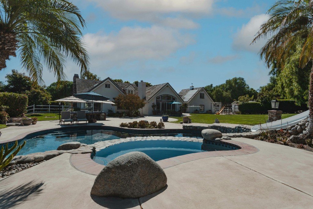 Backyard pool, lawn, and landscaped patio with lounge chairs